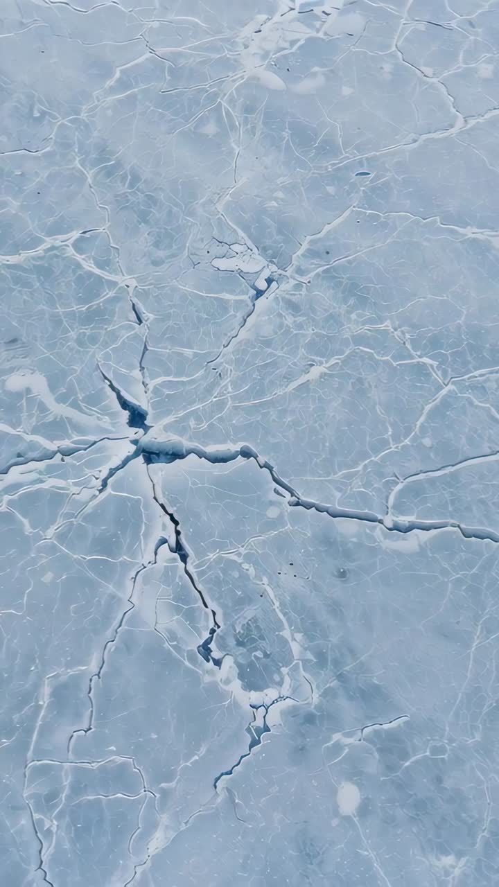 Video verticale: camera con panoramica su un lago ghiacciato dopo l'inizio, che rivela crepe radiali e fessure scure