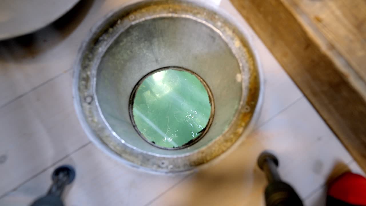 Closeup as fishing lure is lowered into sea through floor hatch inside hotel room in Lofoten