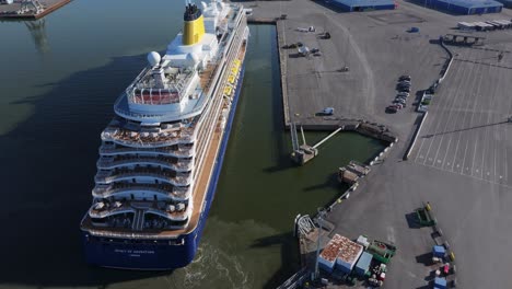 saga cruise ship spirit of adventure arriving to port. vessel approaching quayside. propulsion disturbing bottom sediment. high altitude aerial stern view.