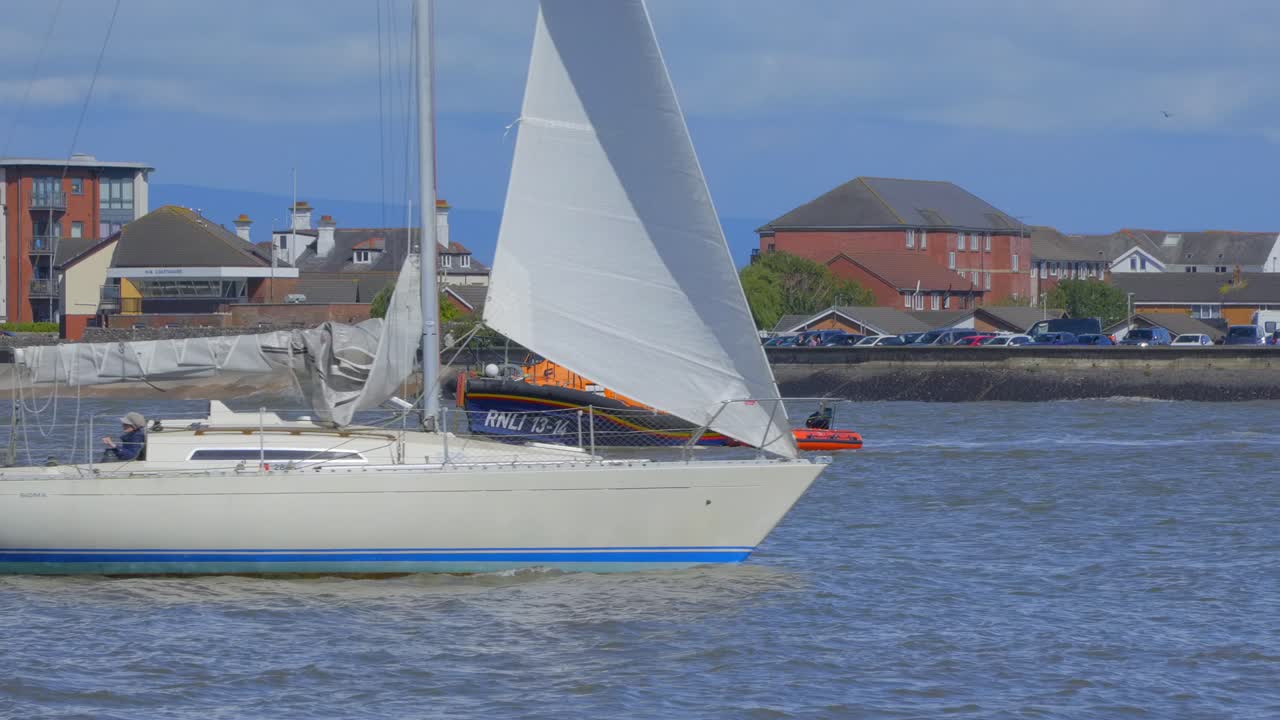 구명 보트 승무원 들 이 상륙 하기 시작 할 때 강 에서 구명 보트 를 지나가는 요트