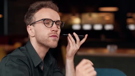 Close-up-portrait-of-a-young-man-listening-to-an-audio-message-on-a-smartphone