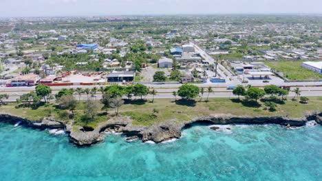 aerial trucking shot of traffic on highway of las americas with blue ocean shoreline in foreground and cityscape in background - santo domingo,dominican republic