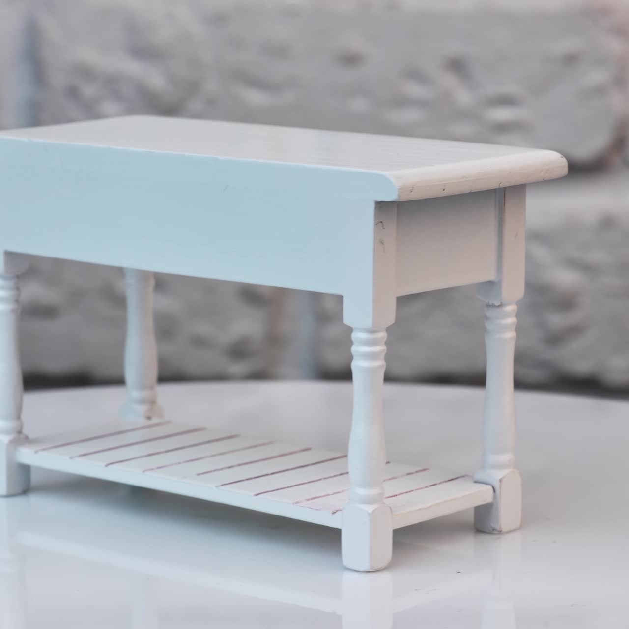 Toy table with three drawers on the turning table. White carved miniature table for a toy house interior. Close up