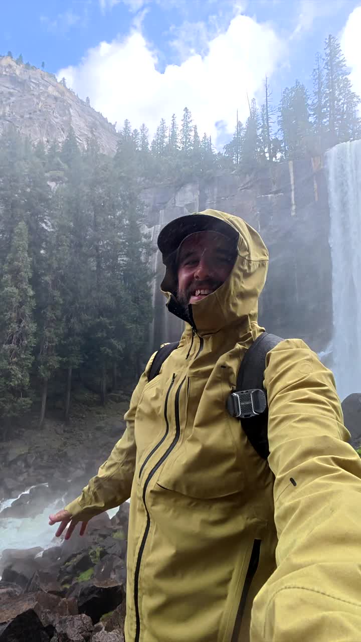 Happy Man Taking Selfie Video in Front of Majestic Waterfall