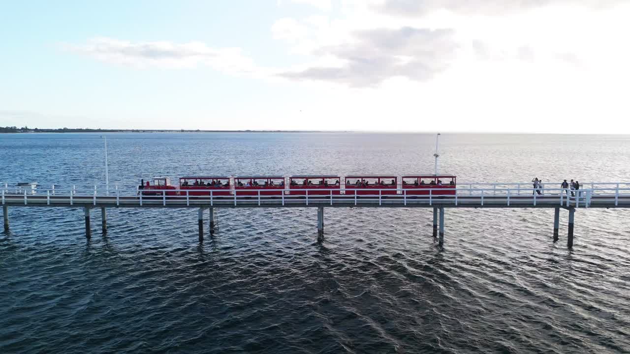 Drone flying alongside the train on Busselton Jetty at sunset