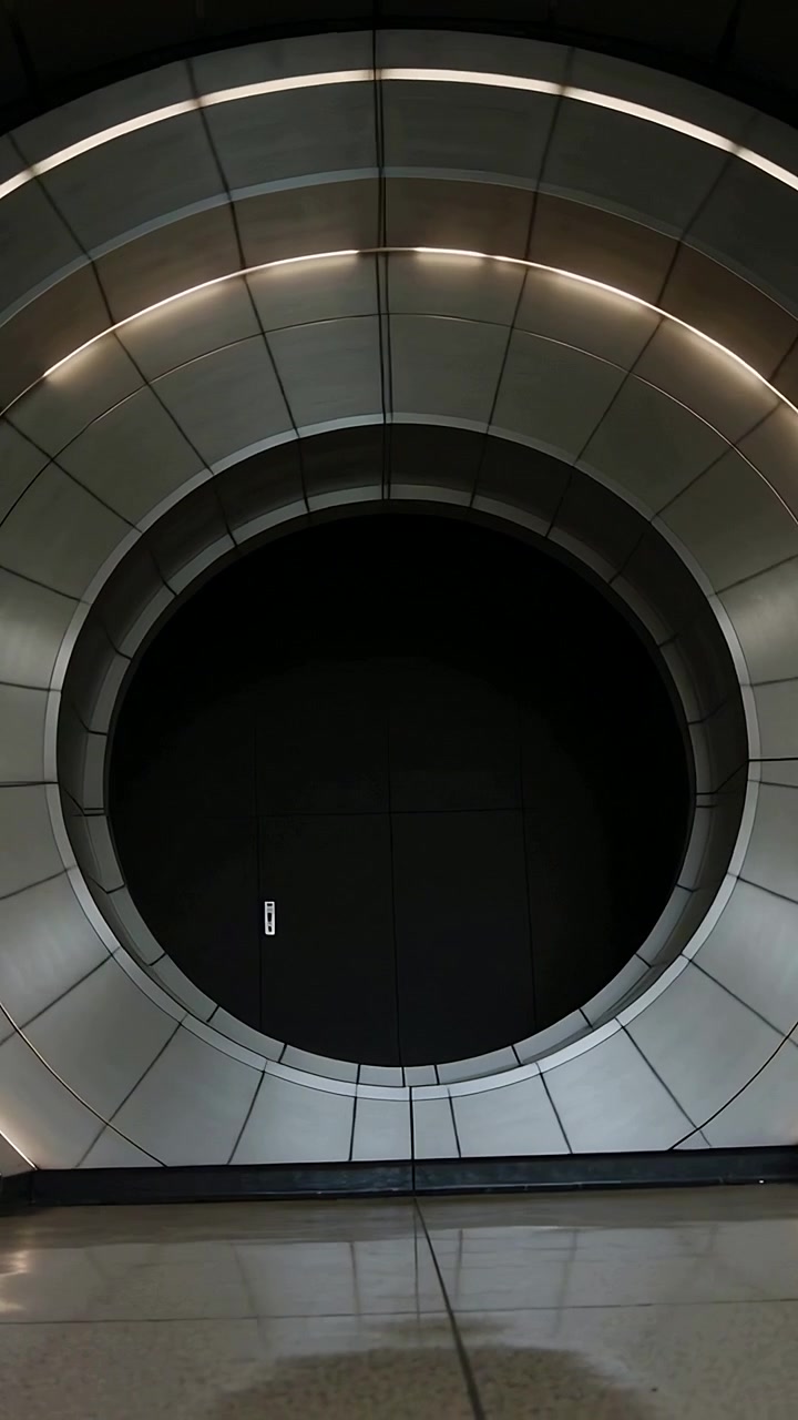 Vertical video: Tilting low camera revealing metal round aperture in terminal, to reveal upper ring