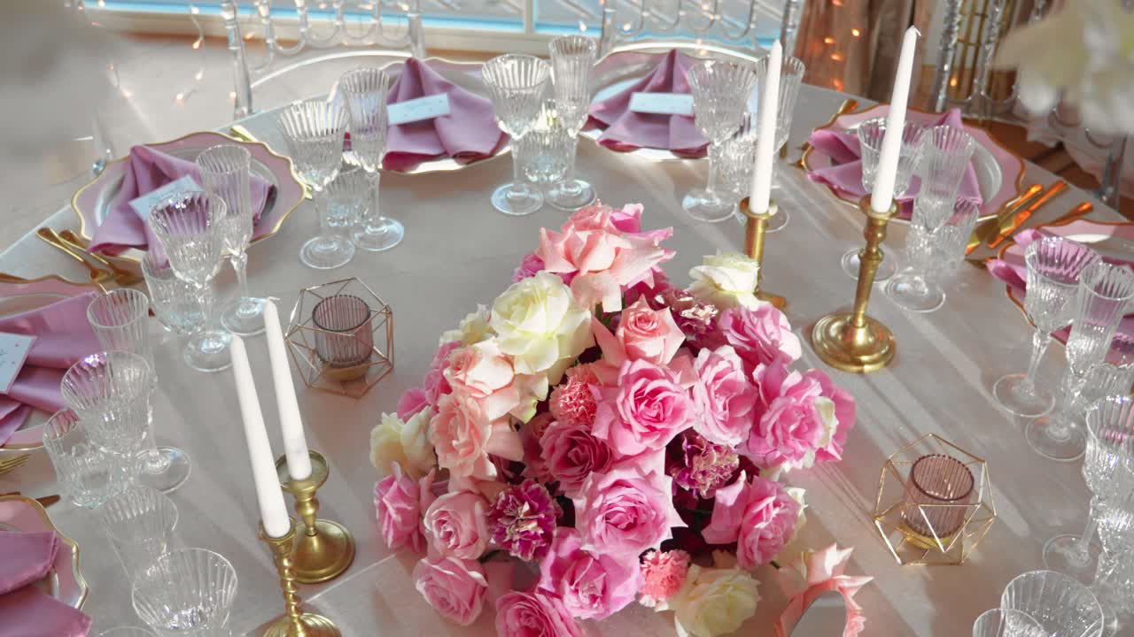 tiro de la mesa de recepción de boda de lujo con vasos y platos, la mesa está decorada con hermosas rosas rosas y blancas y velas blancas, tiro de cerca