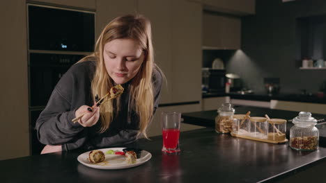 woman eating sushi in kitchen at night