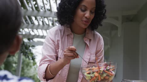 Happy-biracial-mother-and-son-enjoying-meal-at-dinner-table-in-garden,-slow-motion