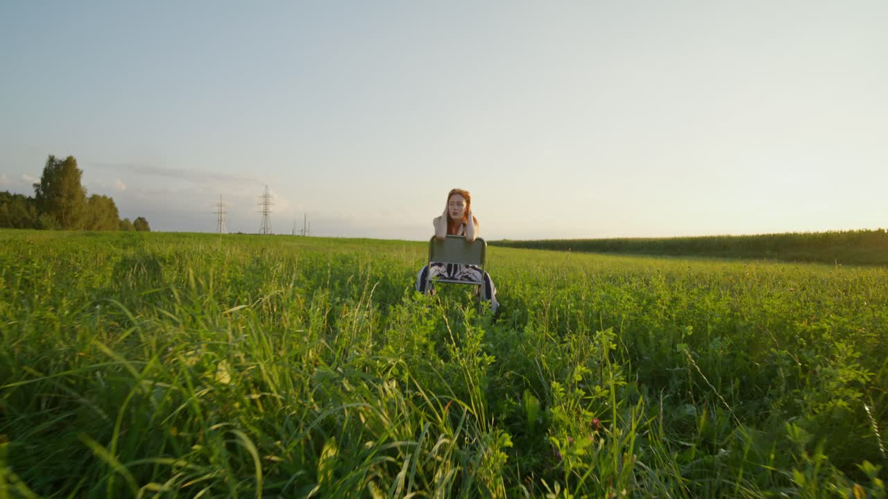 해가 지는 동안 들판에 앉아 있는 여자