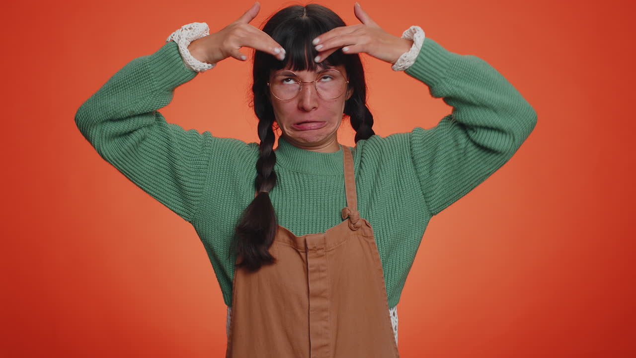 재미있고 즐거운 여자가 장난스럽고 어리석은 표정을 짓고, 찡그린 표정을 짓고, 혀를 보여주는 장난을 칩니다.