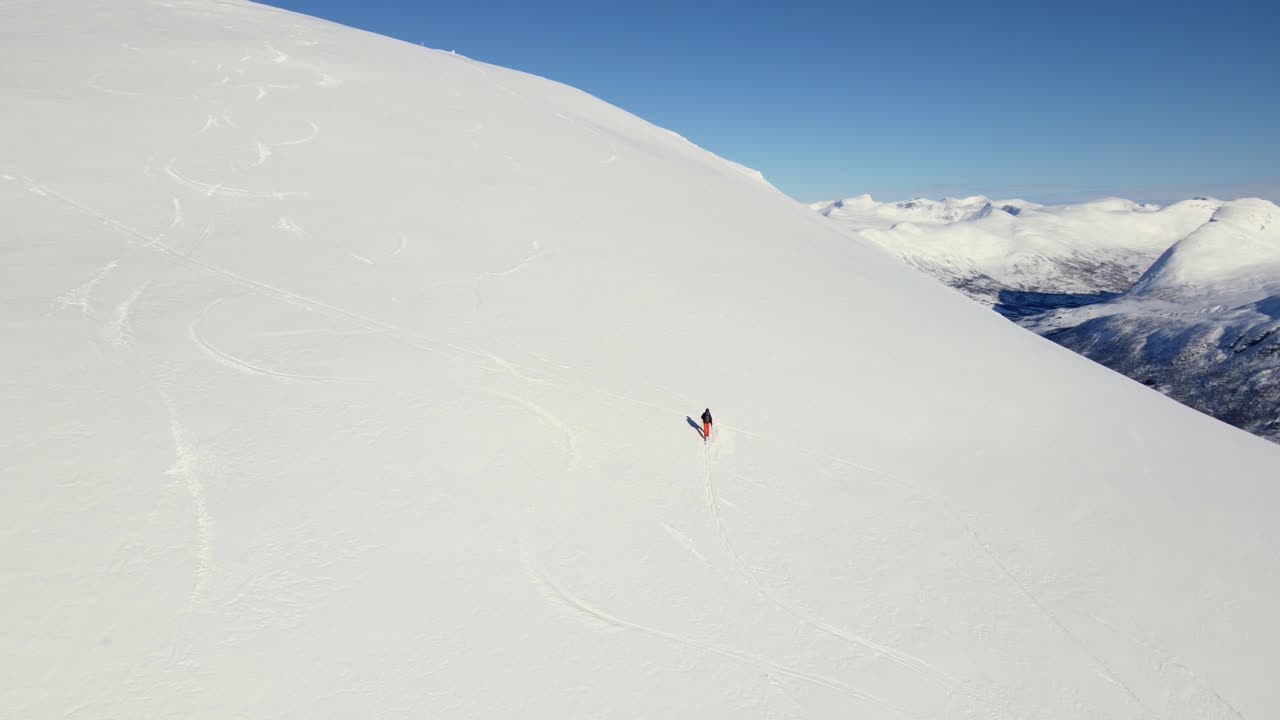 alpinista caminando cuesta arriba montaña nevada durante un día soleado en invierno - noruega, europa - disparo de dron