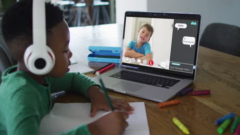 escolar que usa una computadora portátil para la lección en línea en casa, con su colega y el chat web en la pantalla
