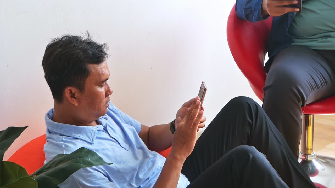 Parents enjoying leisure time with smartphone while scrolling social media in living room