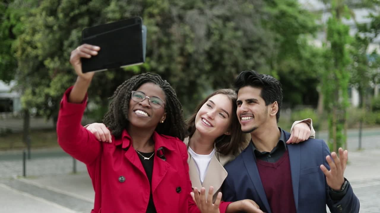 mujeres y hombres haciendo selfies afuera, abrazándose, posando, sonriendo