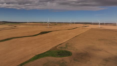 a drone flies across a prairie farmland wind farm to reveal a windmill in southern alberta, canada