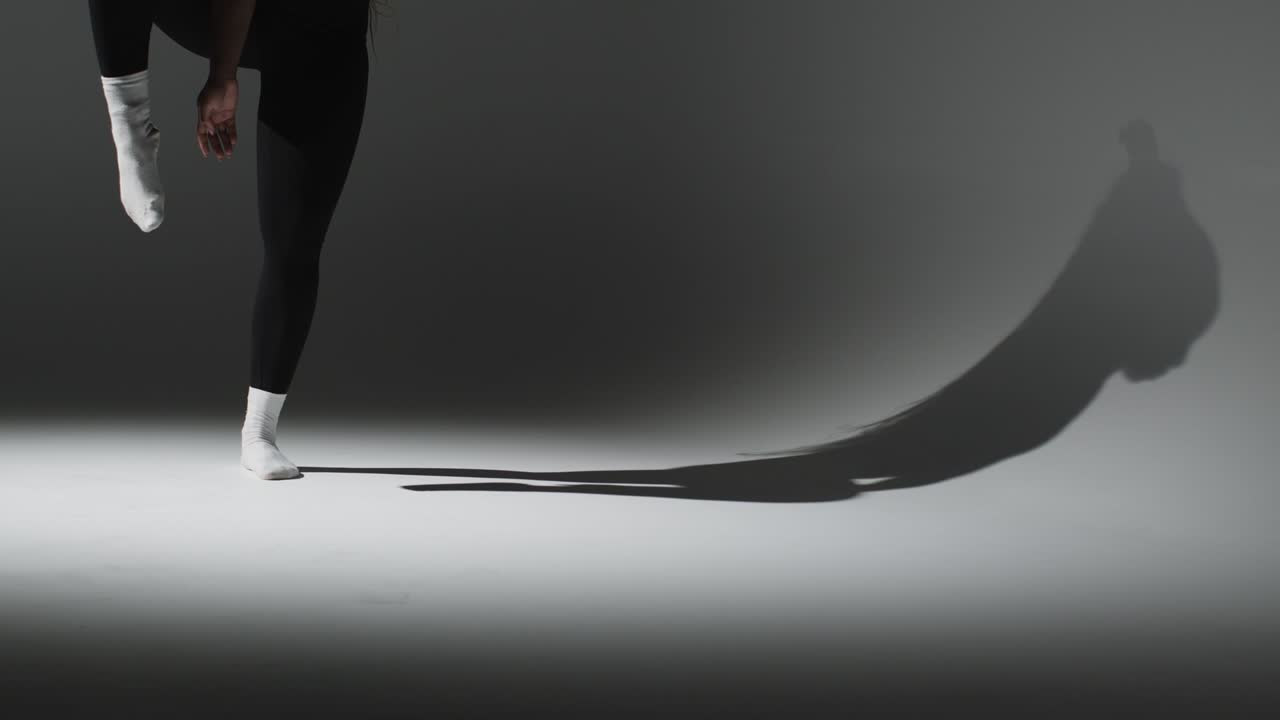 체육관 피트니스 옷을 입은 여성이 그림자와 함께 스트레칭 운동을 하는 클로즈업 스튜디오  ⁇