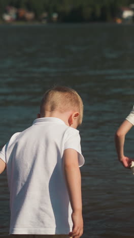 girl in corset to correct posture walks knee deep in water ahead of boy. adventures for children in resort area. daughter carefully holds edges of shorts