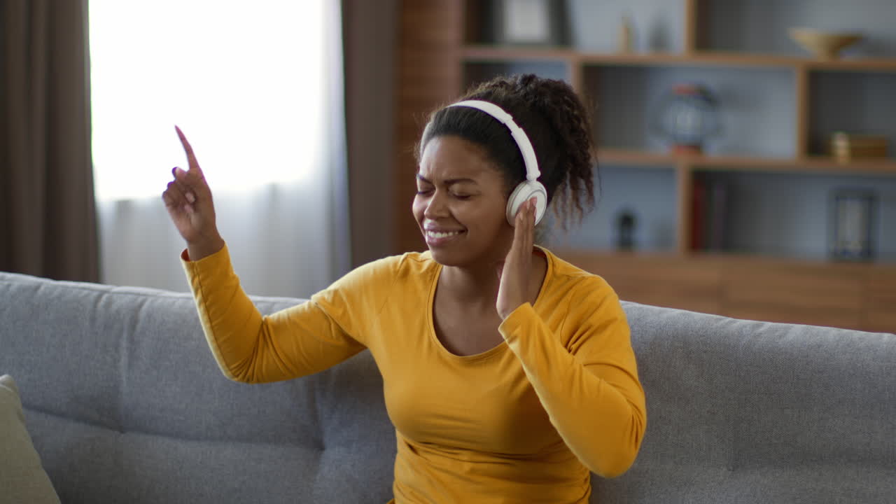 Woman Listening to Music and Dancing on a Couch