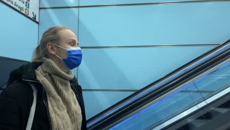 commuter in medical mask on escalator in subway