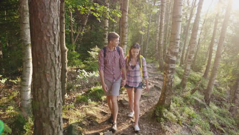 young tourists with backpacks walk along a trail in the forest