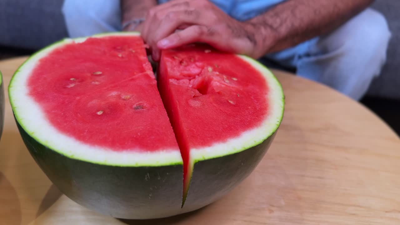Close-up of a knife slicing through a juicy watermelon half on a wooden table, perfect for food, summer refreshment, health, cooking, and lifestyle projects