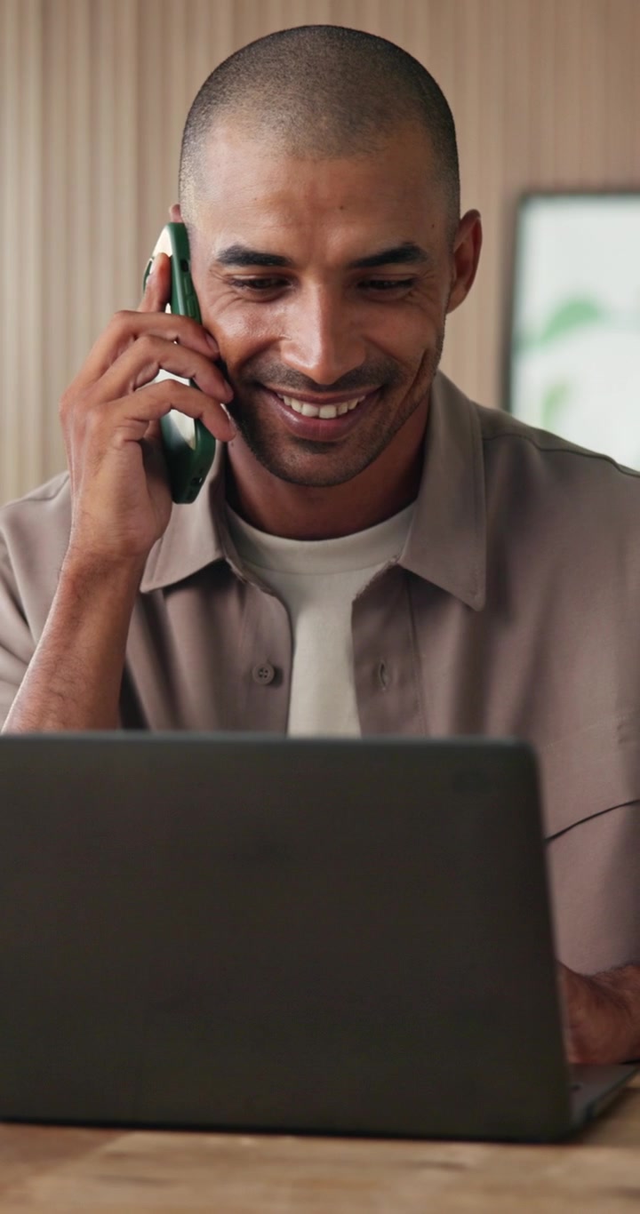 Uomo che Parla al Cellulare Mentre Lavora al Computer Portatile