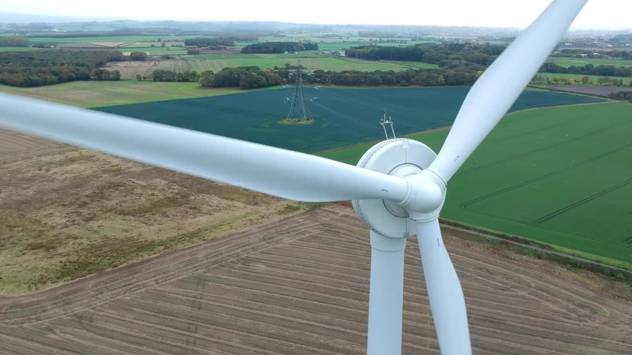 Close up tilting shot of wind turbine, countryside in background