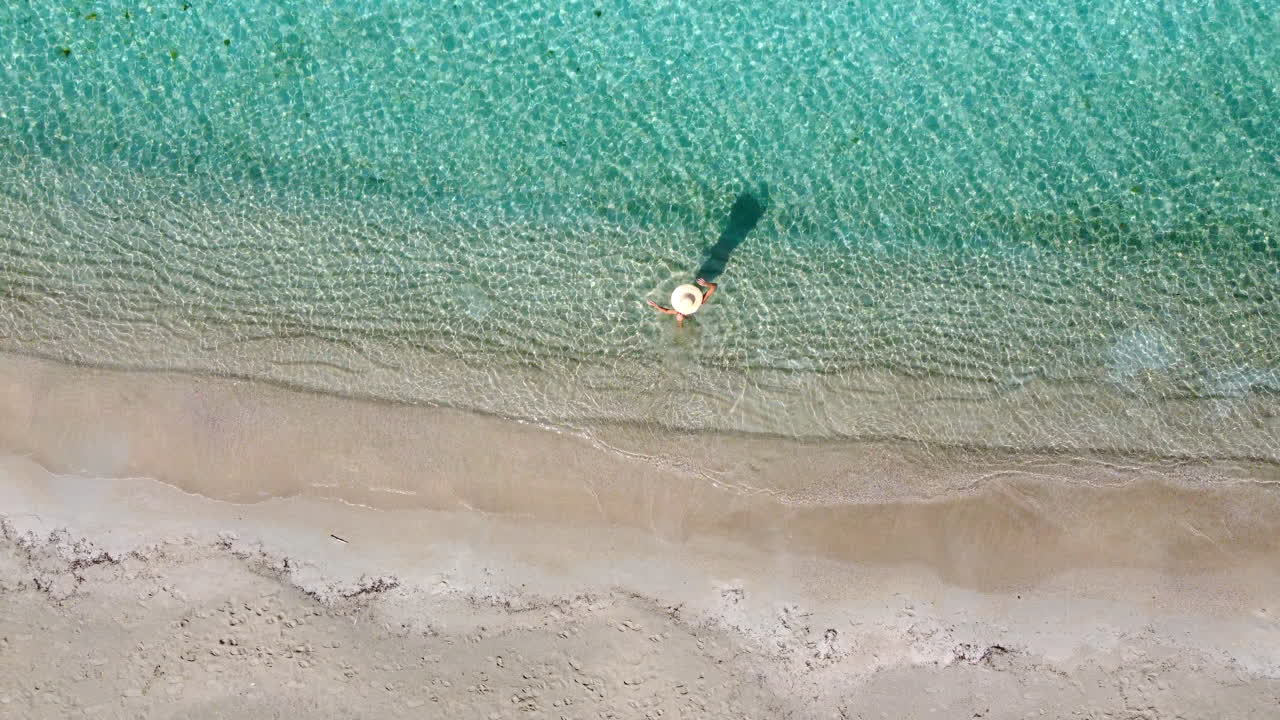 воздушный вид сверху вниз женщины с соломенной шляпой в бирюзовом море рядом с тропическим пустым райским пляжем
