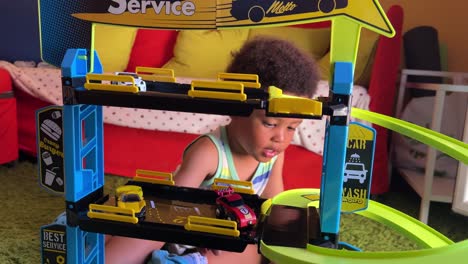 Playful-three-year-old-black-boy-amused-playing-with-his-new-toy-garage-at-home