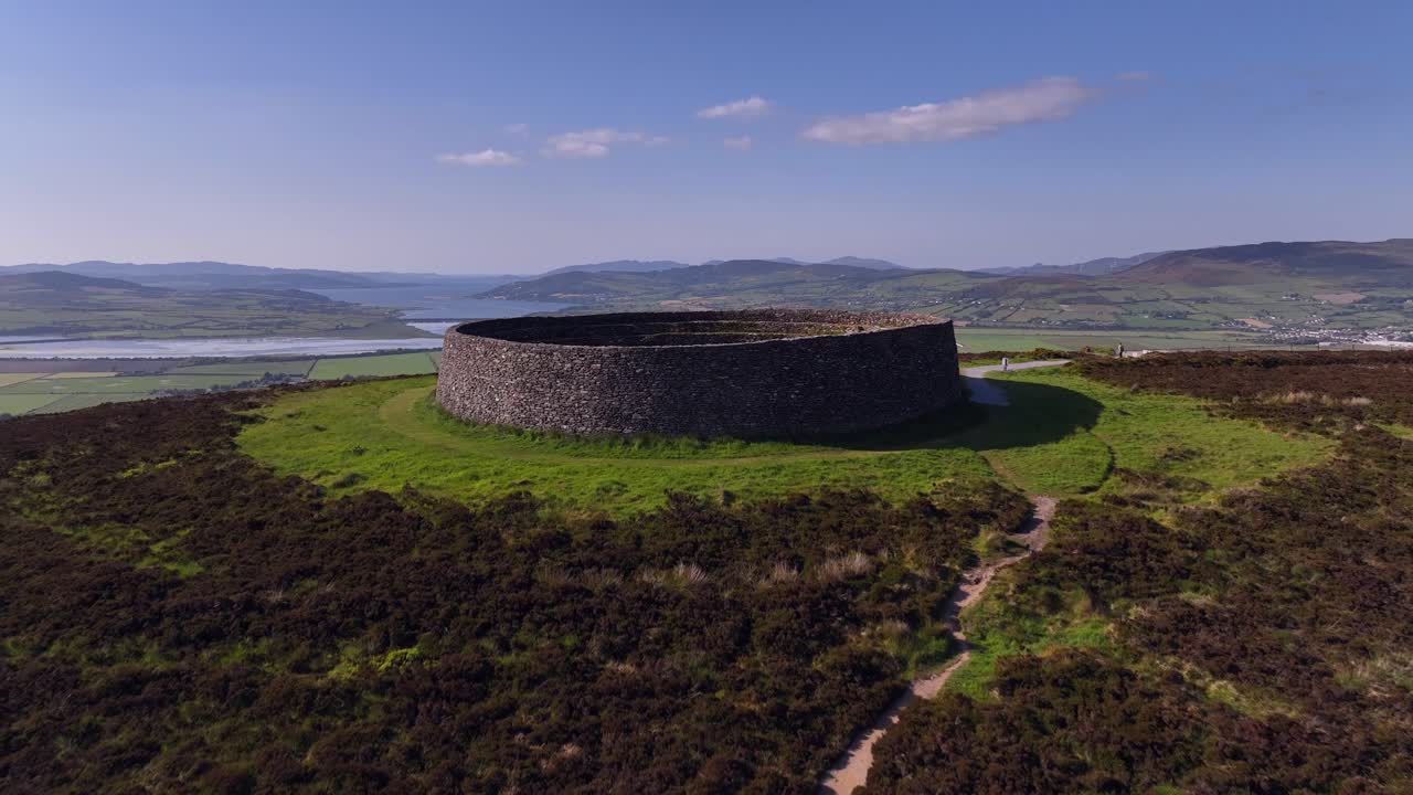 Grianan of Aileach, County Donegal, Ireland, June 2023. Drone descends and pushes forward over the stone ringfort at Inishowen revealing the view north towards Lough Swilly and Inch Wildfowl Reserve.
