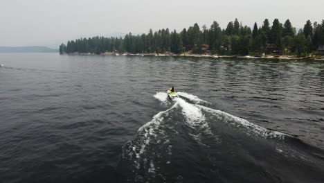 Drohnenaufnahme,-Die-Einer-Person-Folgt,-Die-Einen-Jetski-Am-Payette-Lake-In-McCall,-Idaho,-Fährt,-Mit-Dem-Ufer-Und-Bäumen-Im-Hintergrund