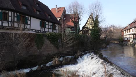 breitbild des weiss-flusses, der durch das mittelalterliche dorf kaysersberg fließt, mit holzbauten, frankreich