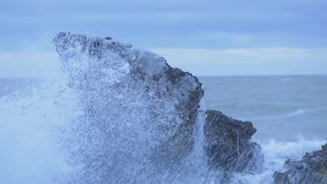 Big-stormy-waves-breaking-against-abandoned-seaside-fortification-building-ruins-at-Karosta-Northern-Forts-in-Liepaja,-slow-motion-medium-closeup