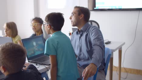 school teacher sitting at desk near children