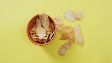 cerrar las papas fritas que caen en un tazón en la superficie amarilla