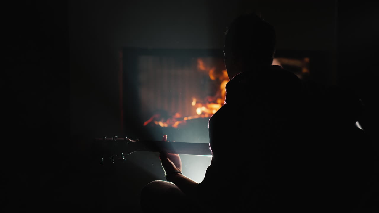 젊은 남자가 벽난로 옆에서 기타를 친다