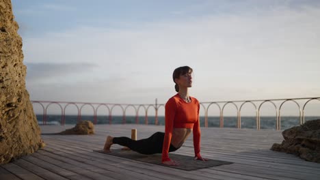 mujer practicando yoga junto al océano