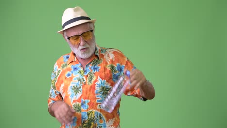 hombre turista barbudo y guapo listo para las vacaciones contra un fondo verde