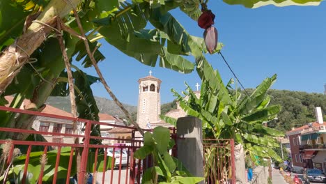 Saint-Nicholas-Orthodox-church-tower-viewed-through-banana-trees-leaves,-Parga