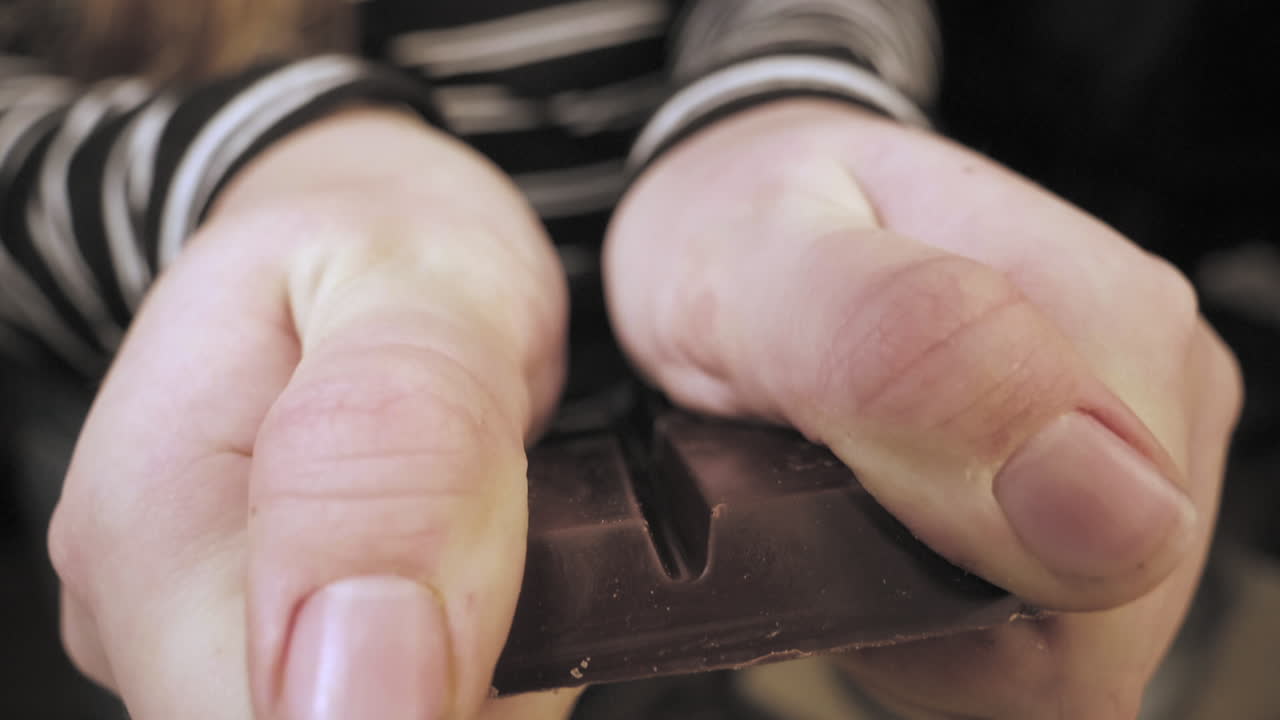 Slow Motion of female hands preparing chocolate cookies breaking dark chocolate.
