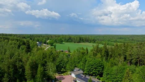 Aerial-view-away-from-a-modern-house-in-middle-of-forest-greenery,-summer-day