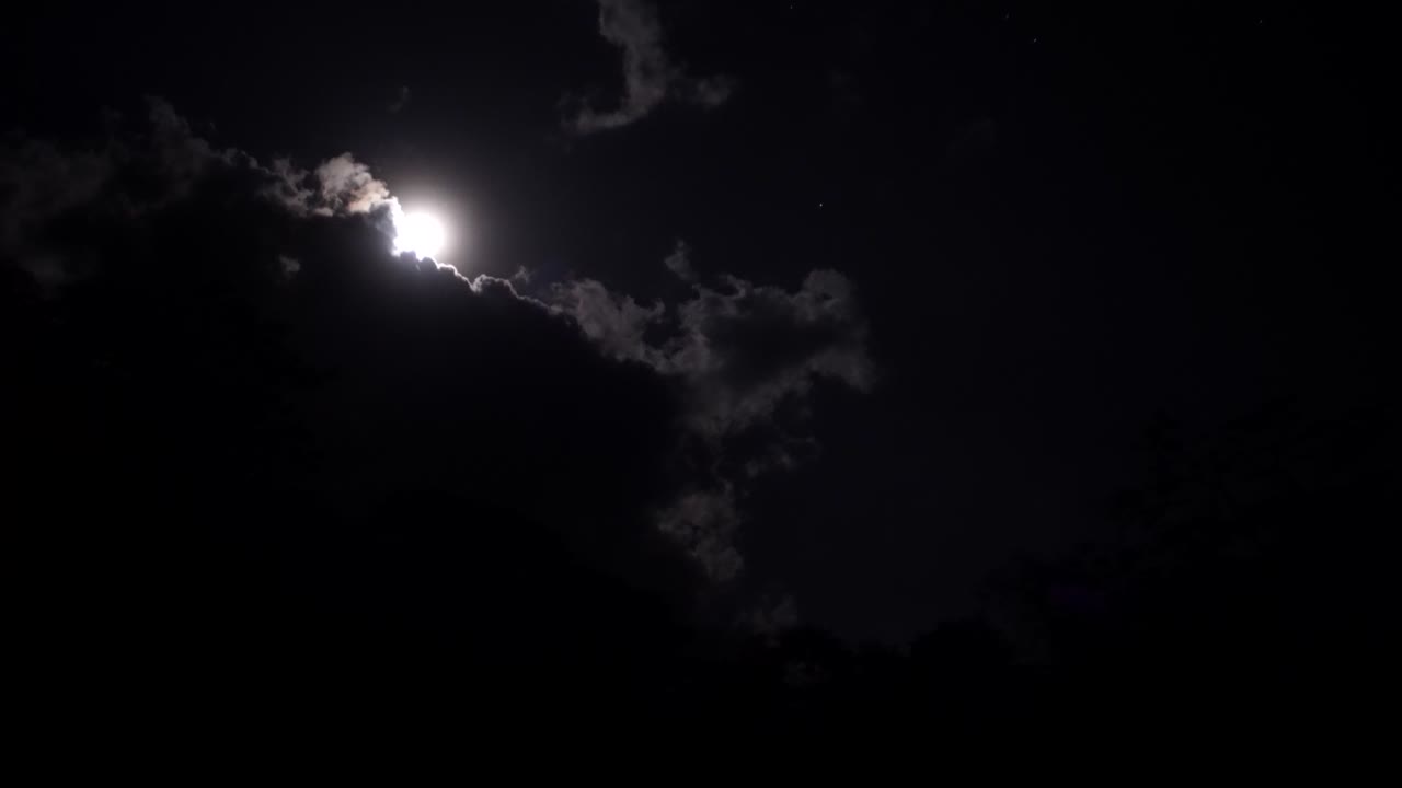 Full Moon Shining Through Dark Clouds at Night