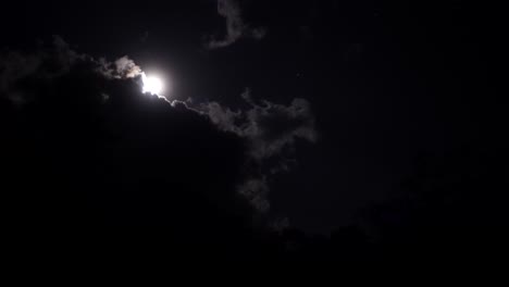 full moon shining through dark clouds at night