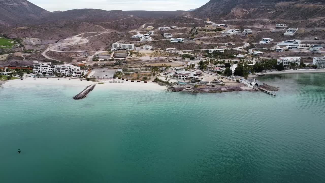 panorámica aérea tomada sobre la hermosa costa de playa el caymancito cerca de la paz baja california sur méxico con vista al paisaje seco y al edificio del hotel con mar turquesa