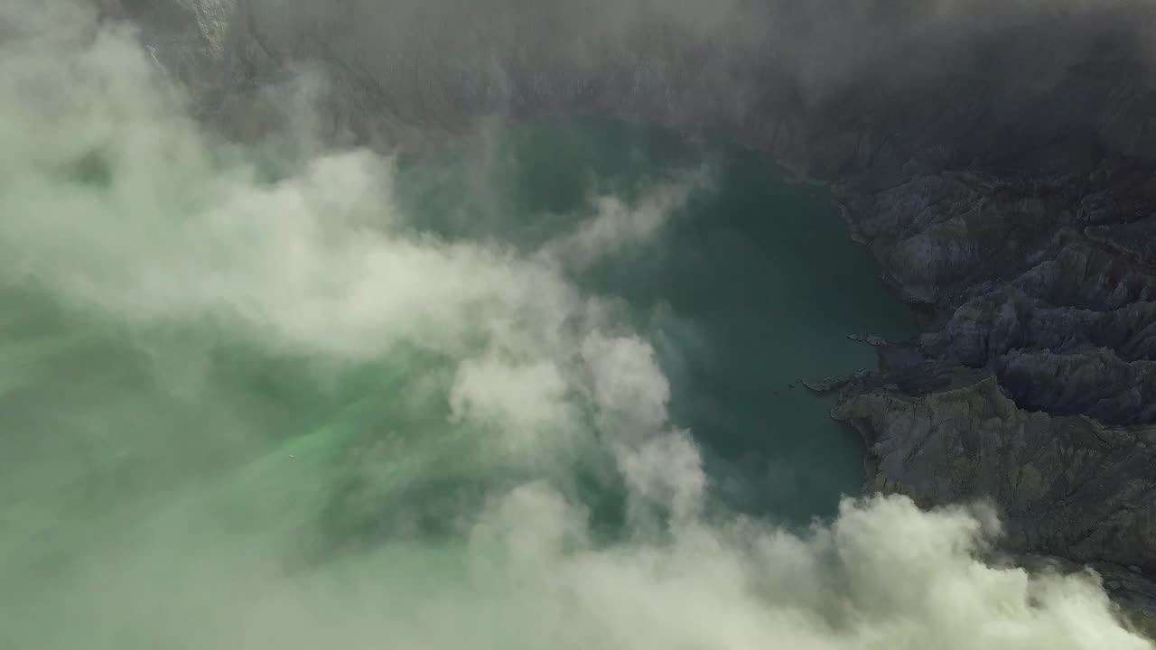 panorámica aérea de un lago ácido con humo dentro de un volcán