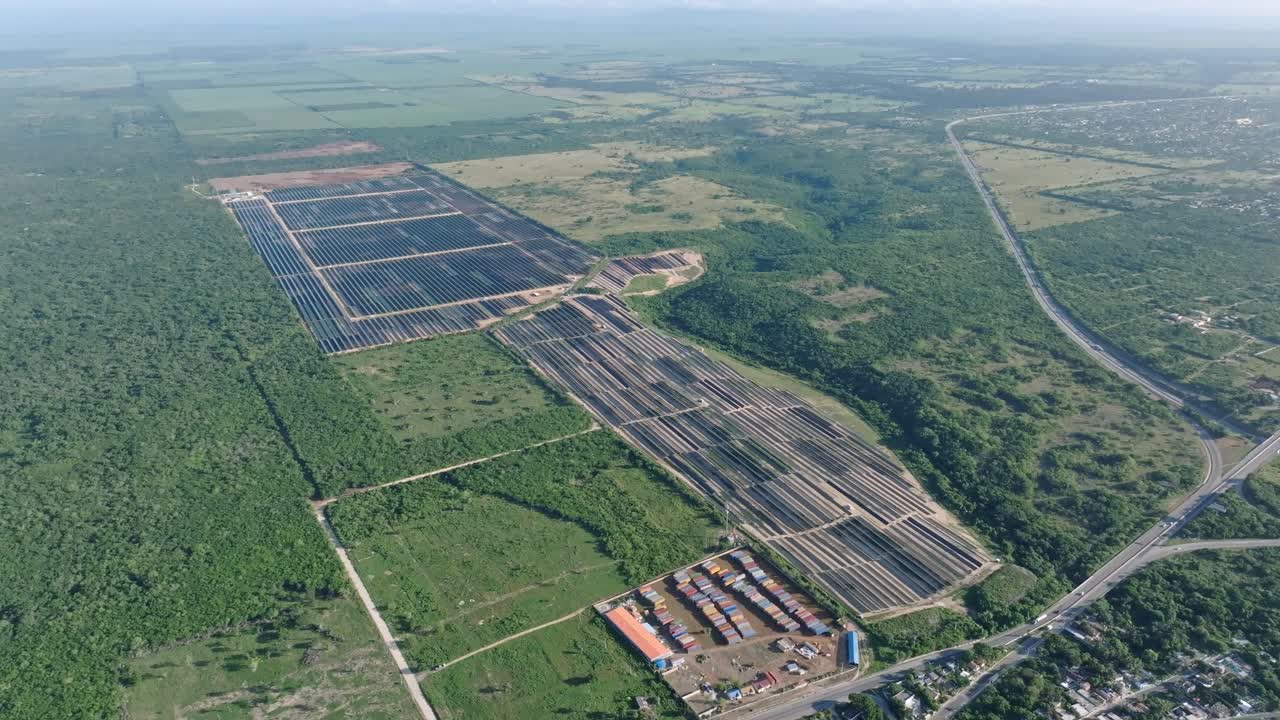 Aerial view of solar panels surrounded by green vegetated fields during sunny day in La Romana