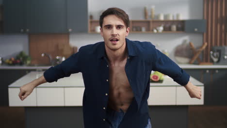 attractive man dancing at home kitchen. sexy man in open skirt posing to camera