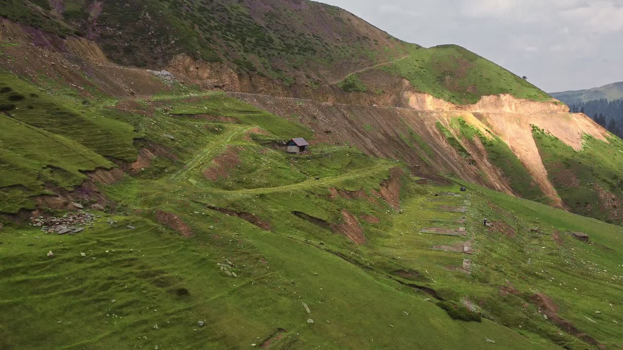 un panerian que muestra una cabaña de madera solitaria en un prado verde en la montaña cerca de peer ki gali, cachemira