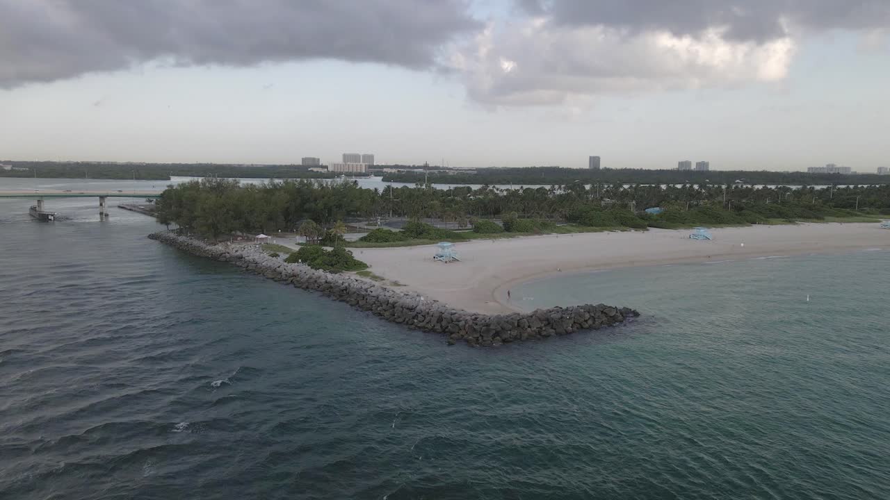 aéreo: hombre solitario lanza una red de peces desde la playa en el parque para perros de la playa de haulover